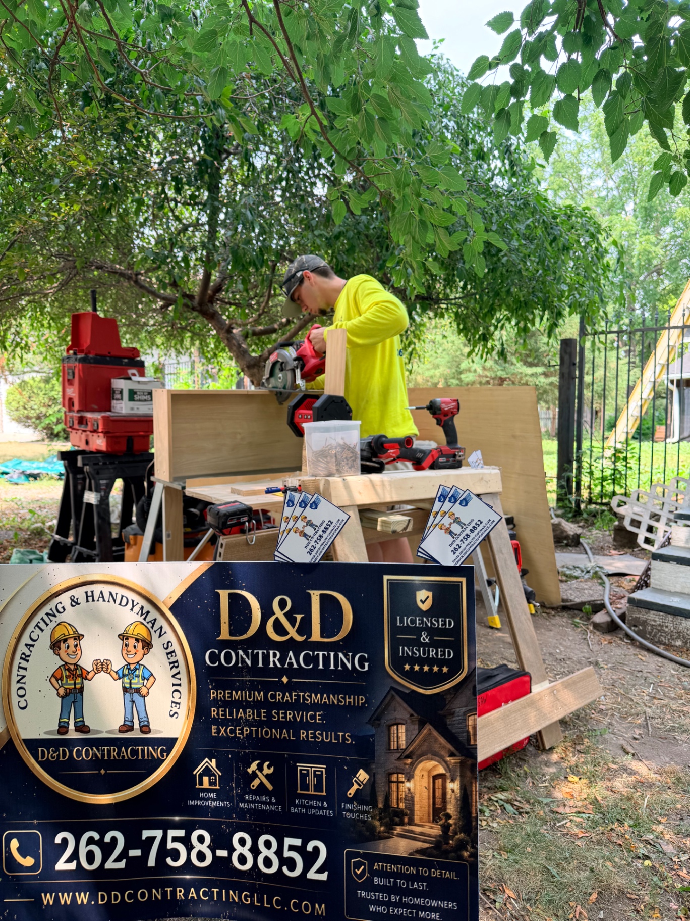D&D Contracting owner cutting lumber at a job site next to the company sign
